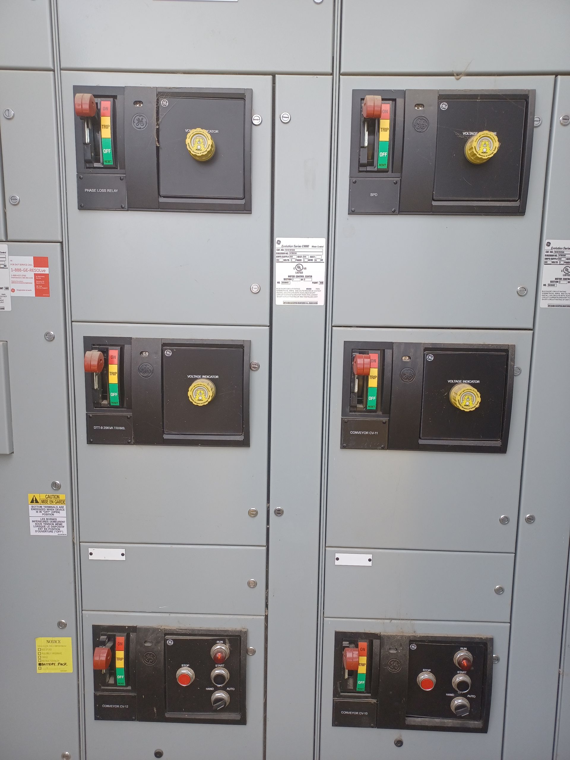 Electrical panel with multiple gray enclosures, each with switches and dials, and indicator lights.