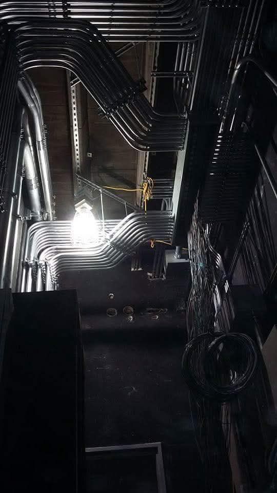 A bunch of pipes are hanging from the ceiling of a building.
