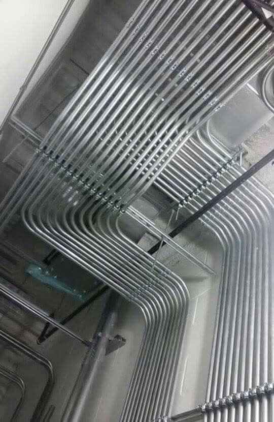 A bunch of metal pipes are hanging from the ceiling of a building.