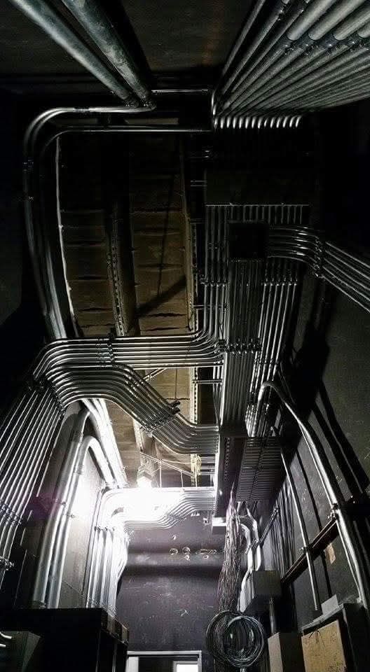 A dark room with a lot of pipes hanging from the ceiling.