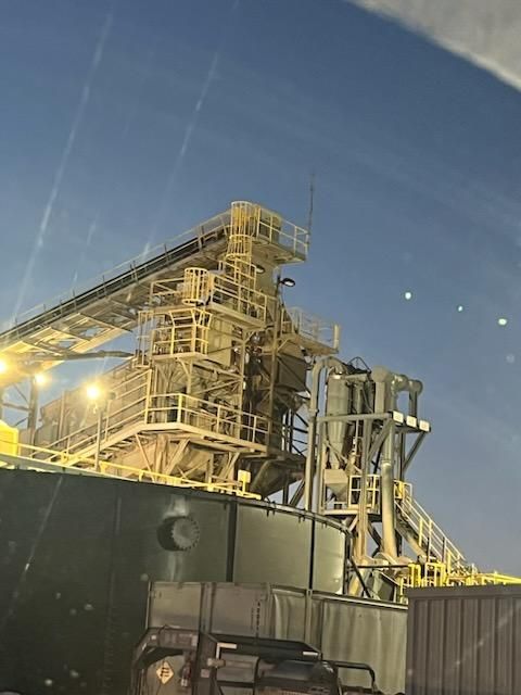 Large industrial structure, likely a ship, with yellow metal framework against a dusky sky.