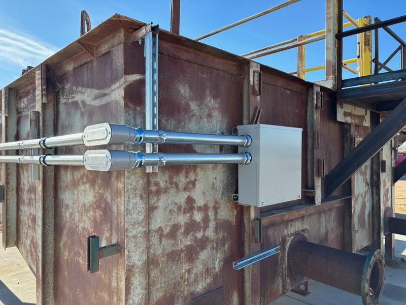 A rusty metal building with pipes and a box on the side.