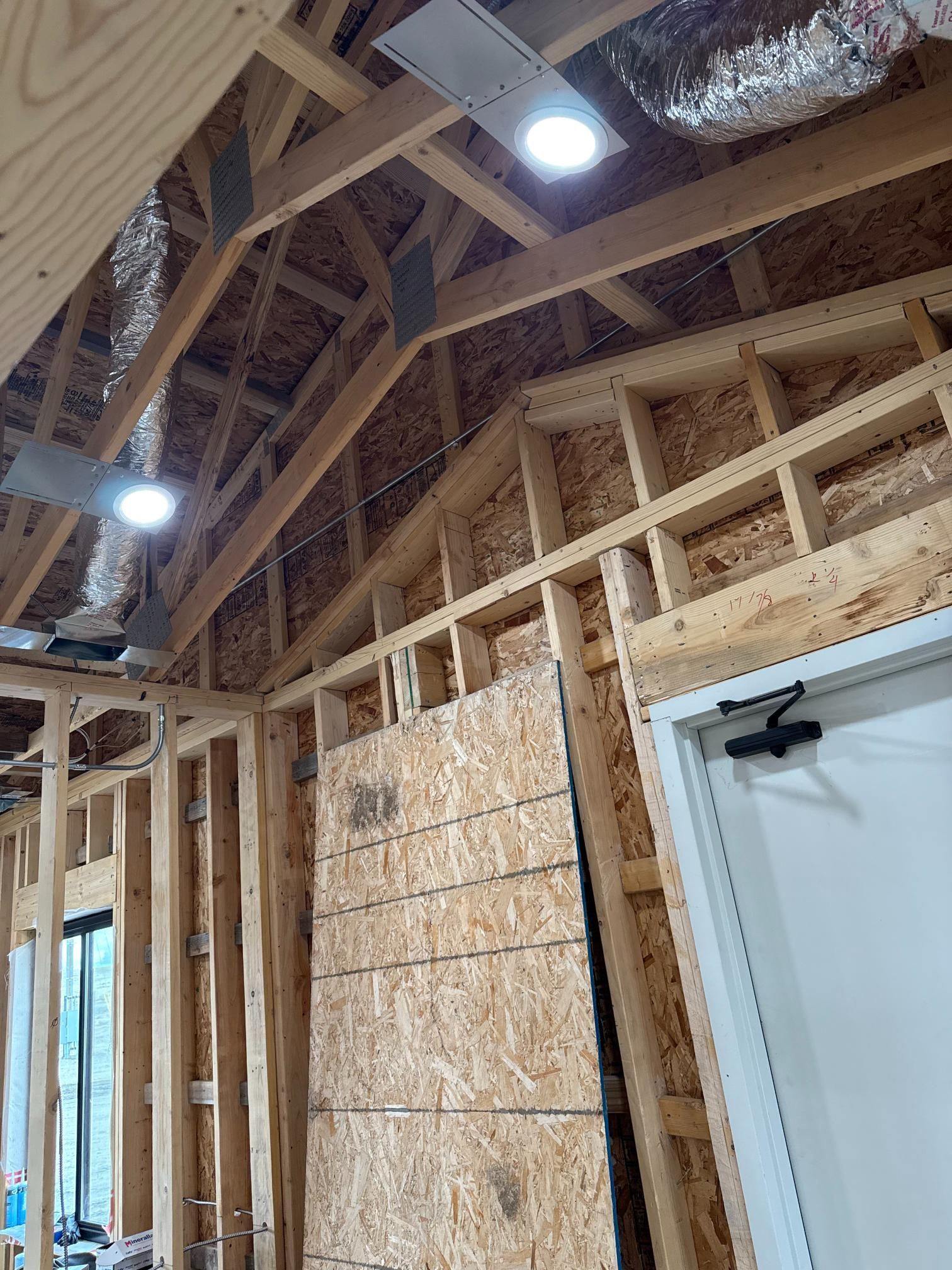 Interior view of a building under construction, showing wooden framing, roof, and a door frame.