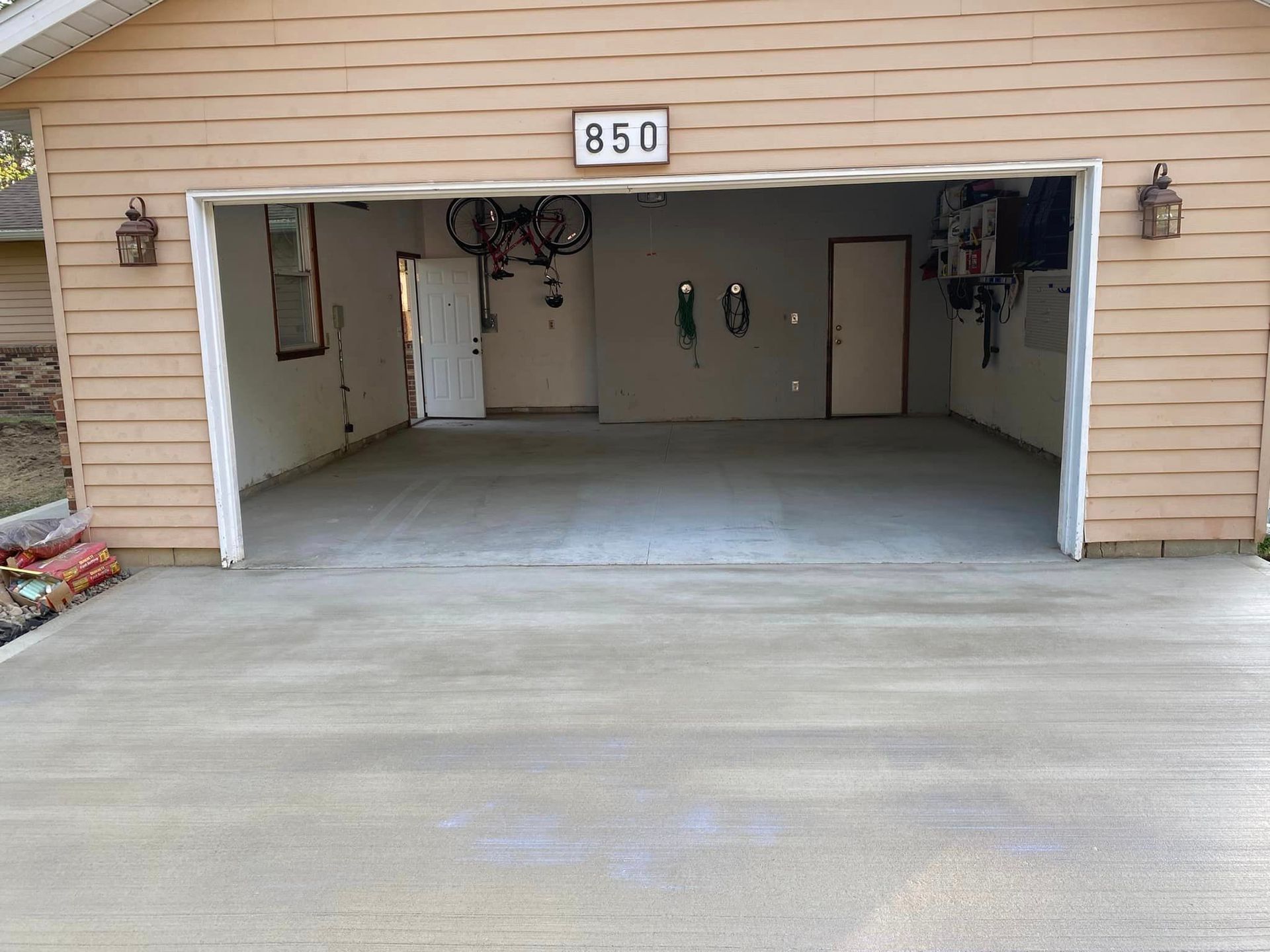 A garage with a concrete driveway and a bicycle hanging from the door.