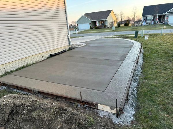 A concrete driveway is being built in front of a house.