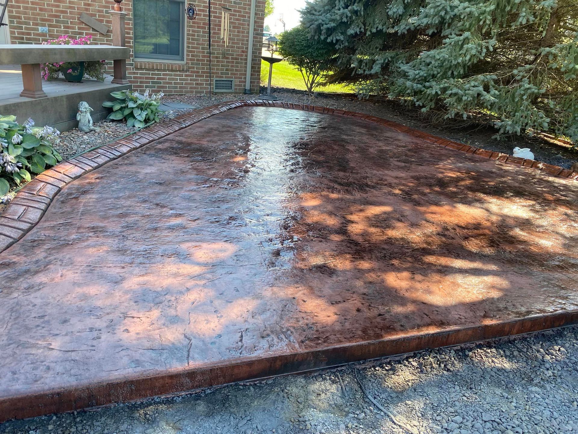 A concrete driveway with a brick walkway in front of a brick house.