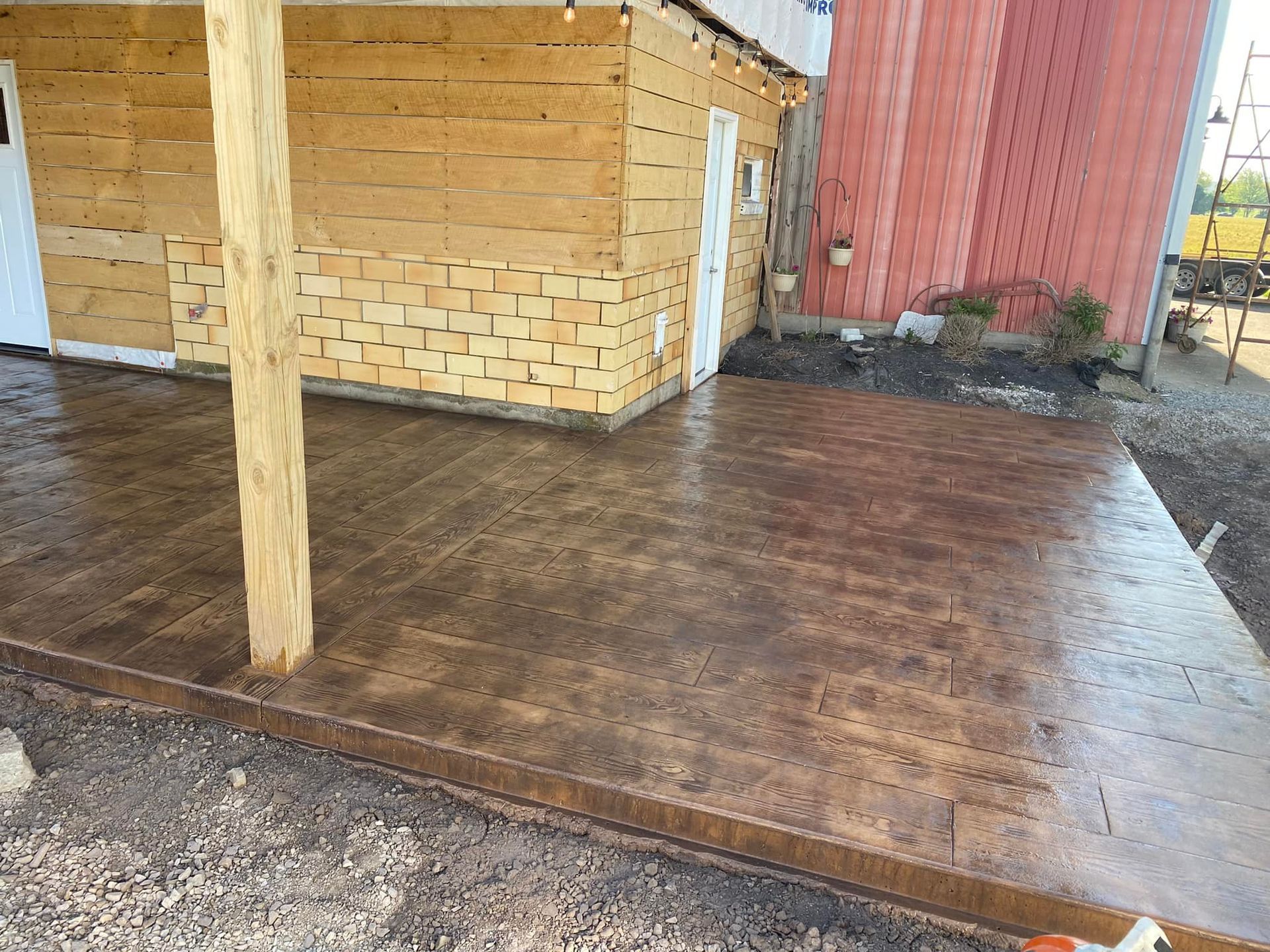 A concrete patio with a wooden building in the background.
