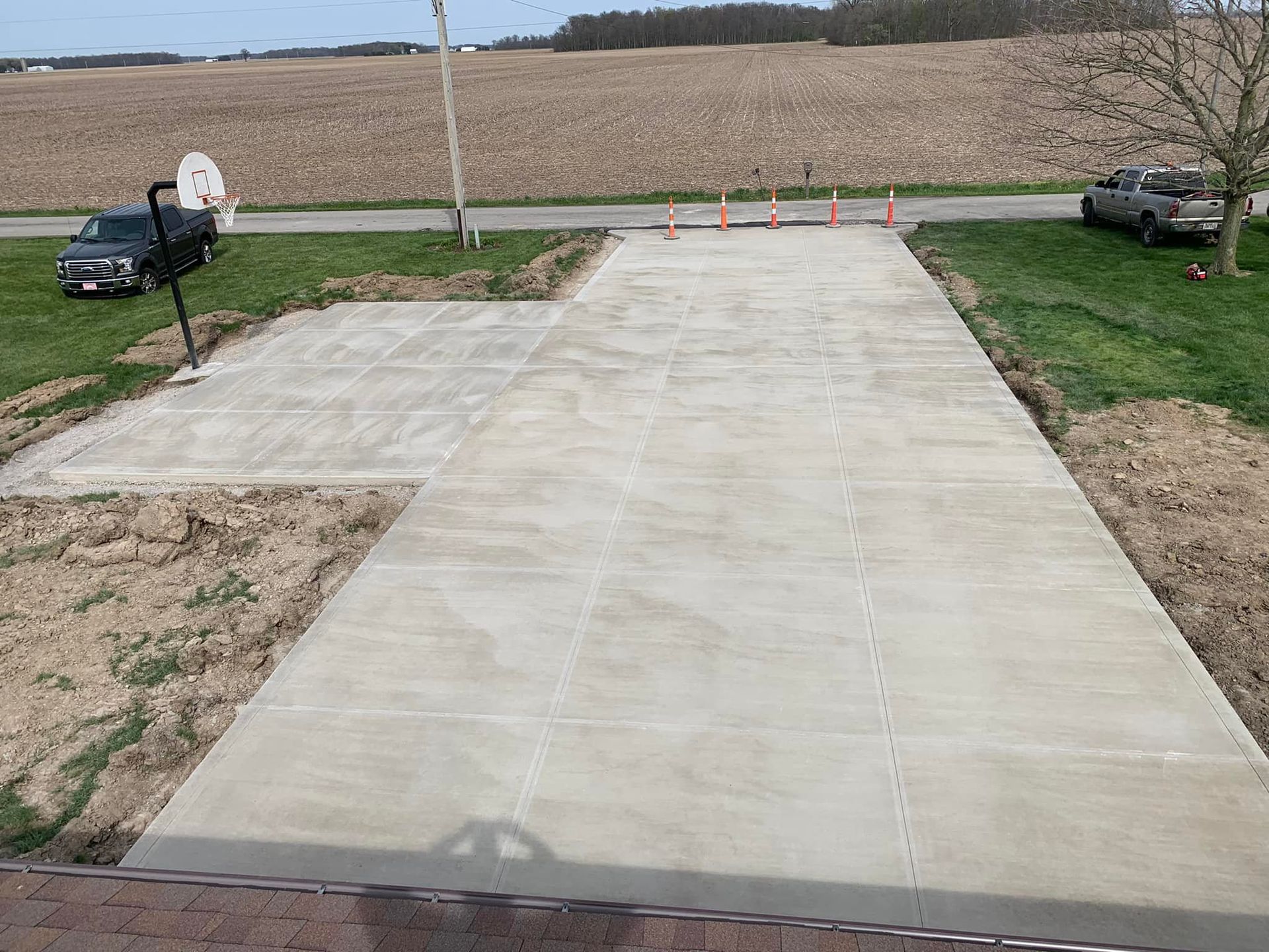 A concrete driveway with a basketball hoop in the middle of it.