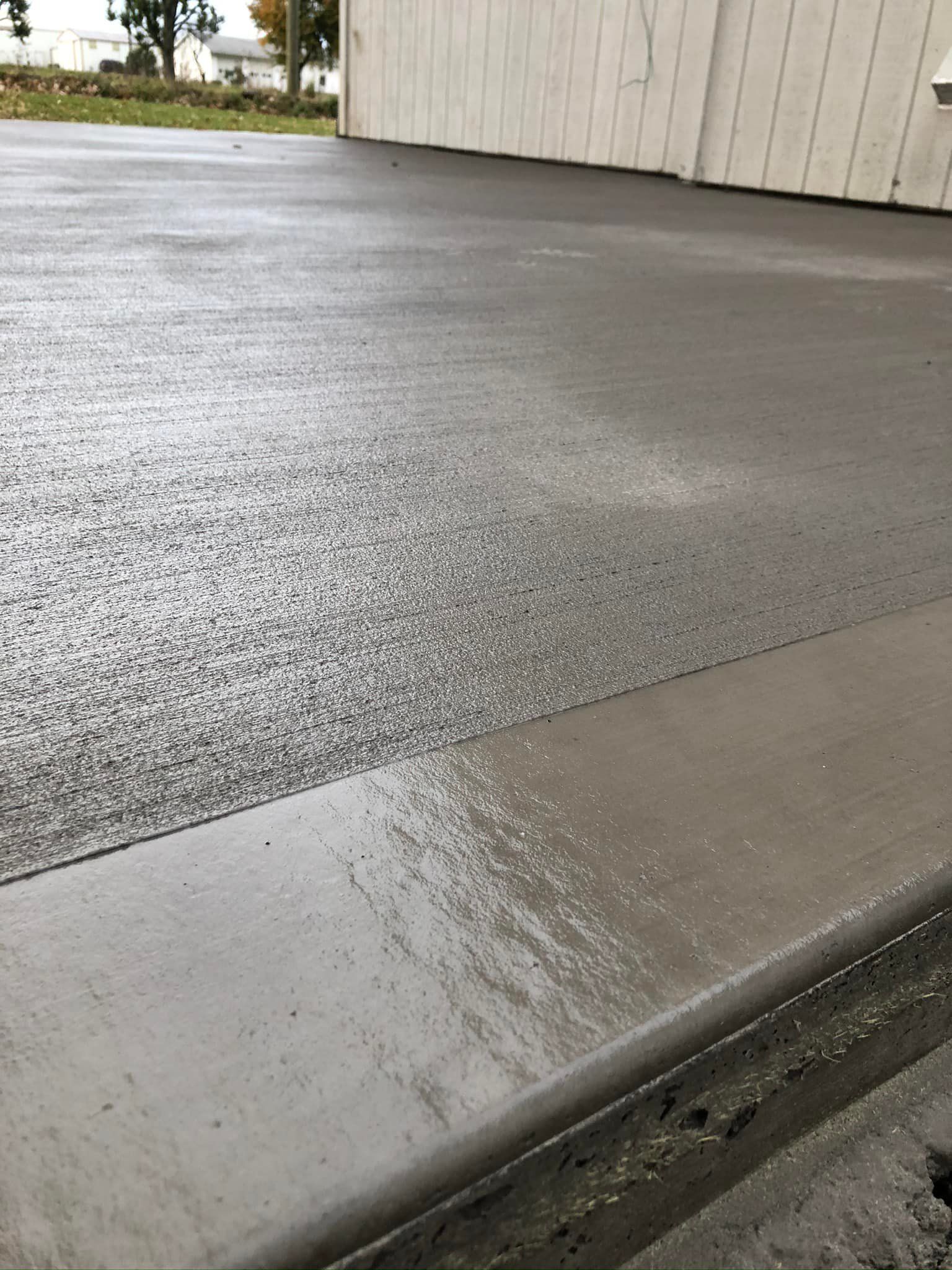 A concrete driveway with a white garage in the background.
