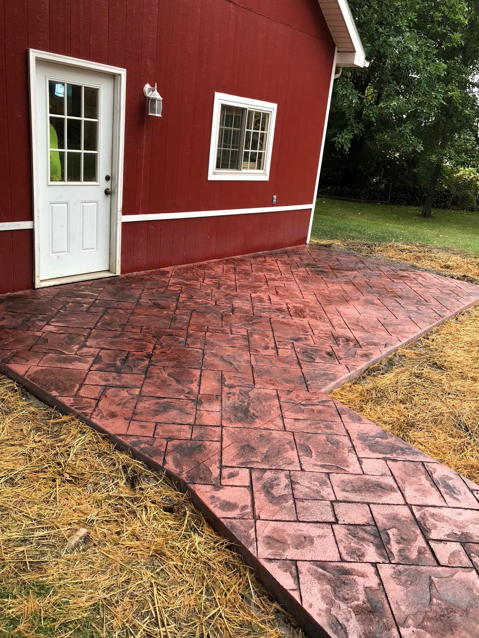 A red barn with a concrete walkway leading to it.