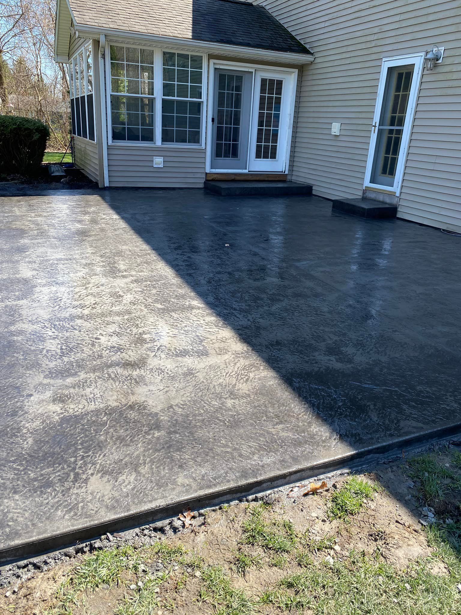 A concrete driveway in front of a house with a porch.