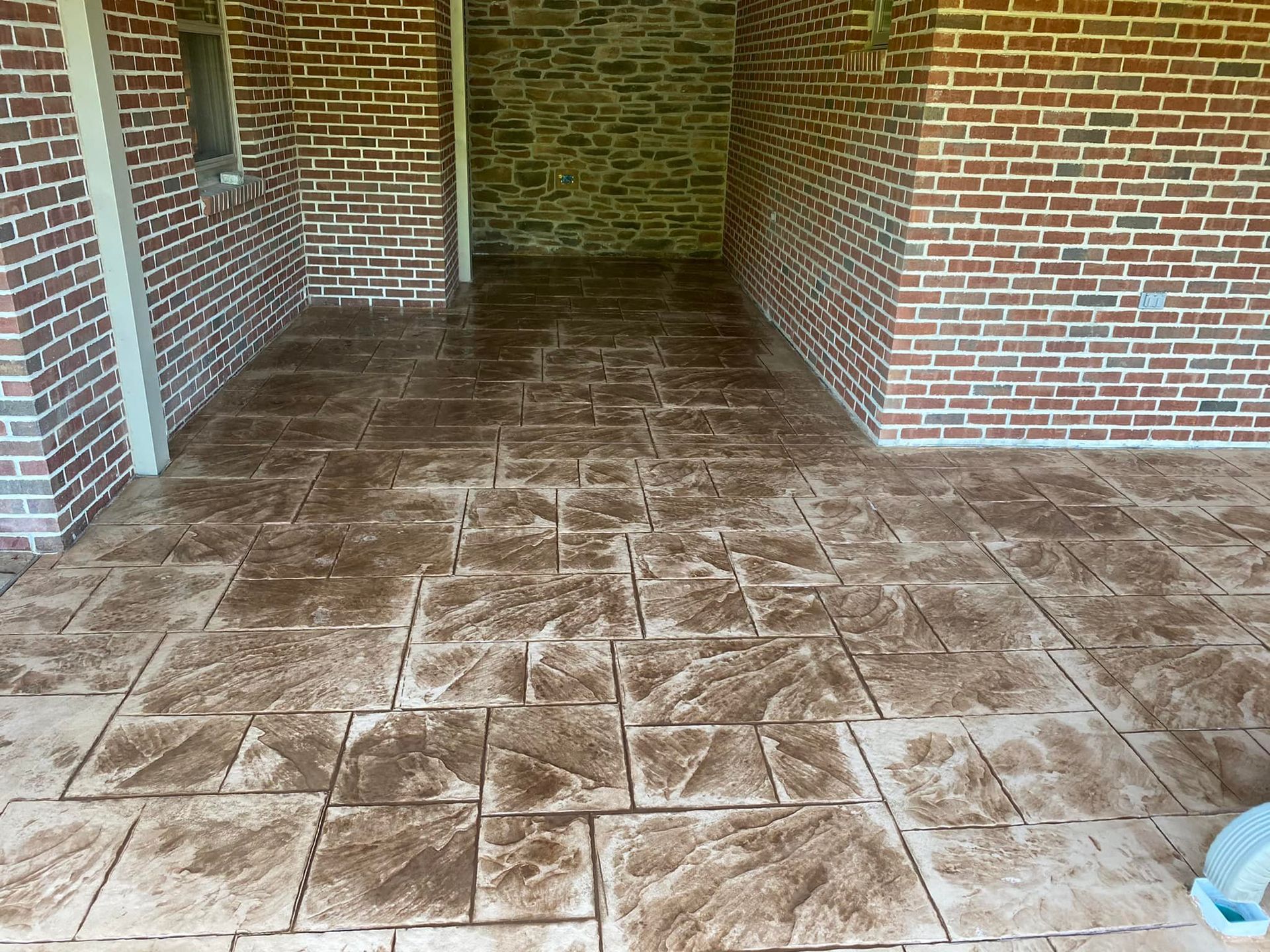 A brick wall with a concrete floor in front of it.