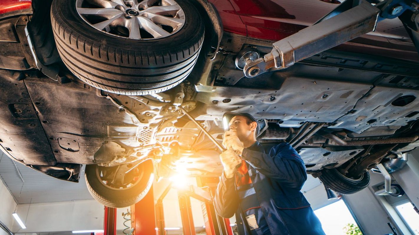 A man is working on the underside of a car in a garage.