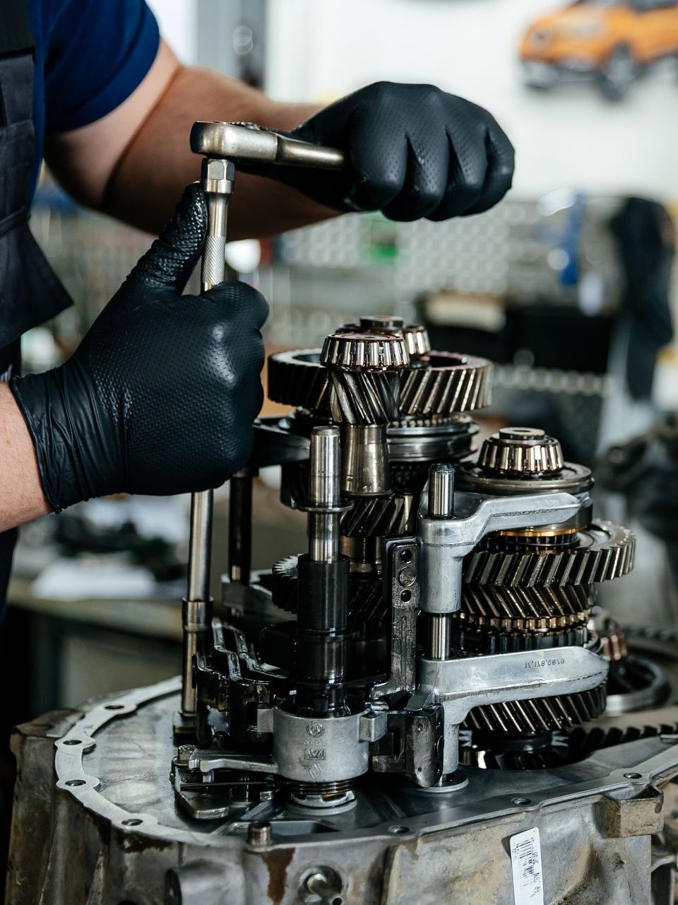 A man is working on a gearbox with a wrench.