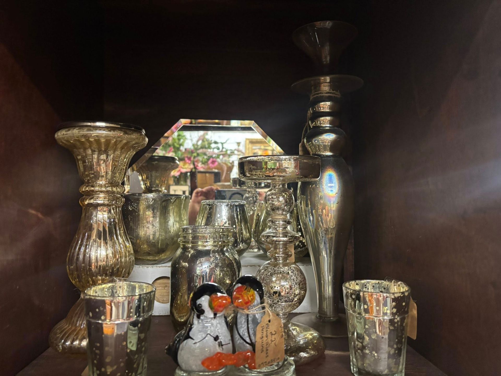 various decorative glassware, mostly silver and gold, with a couple of penguin figurines.