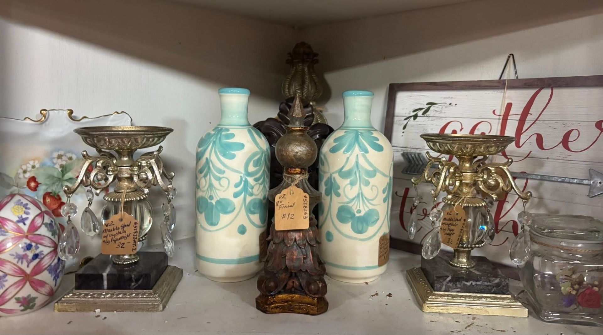 Shelf with decorative items: teal patterned bottles, candle holders, and a 