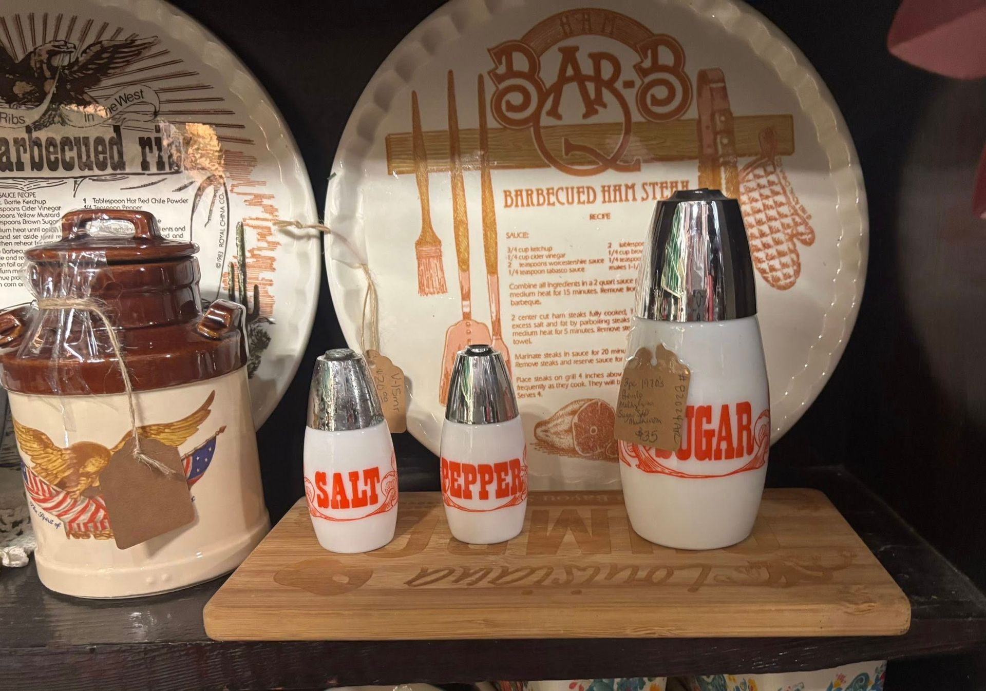 Salt, pepper, and sugar shakers on a wooden board with a vintage milk jug and plates 