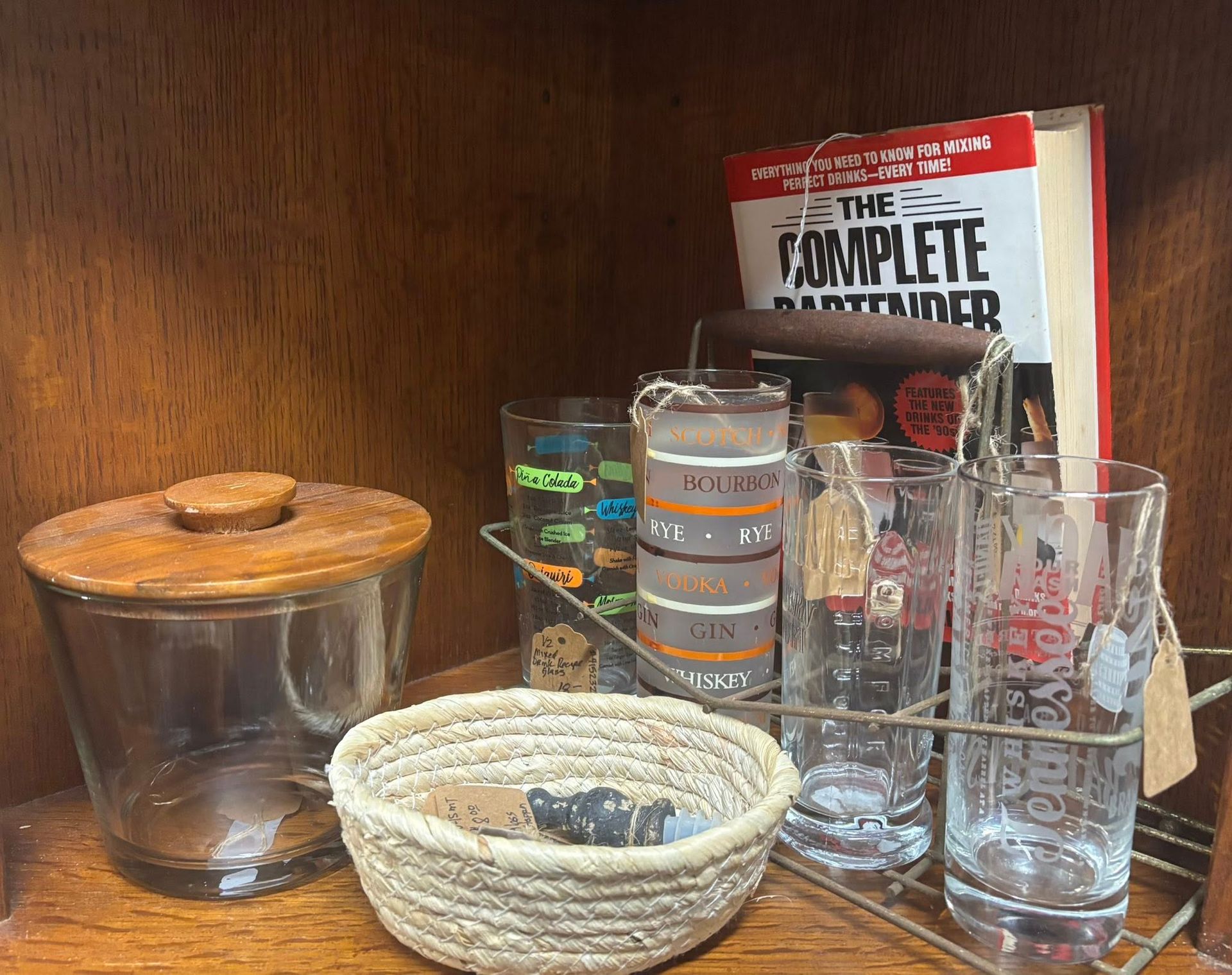 Shelf with vintage glassware, a book, and a wooden lidded jar.