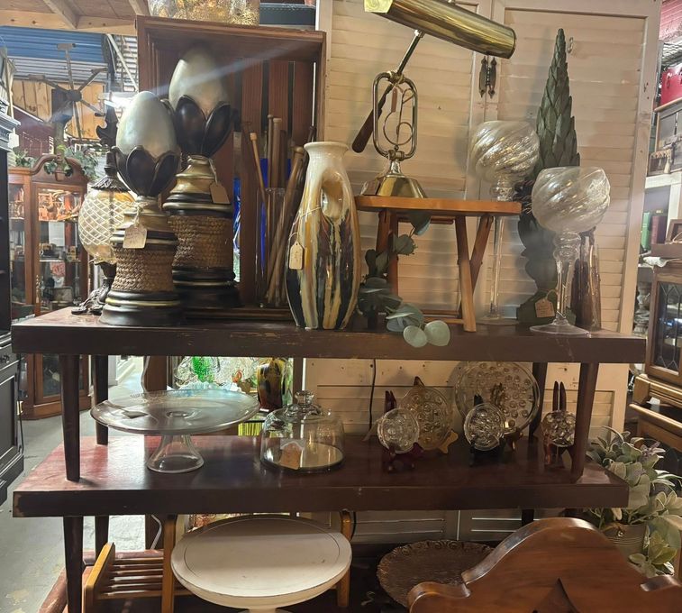 Shelves displaying vintage lamps, vases, and glassware in a shop.