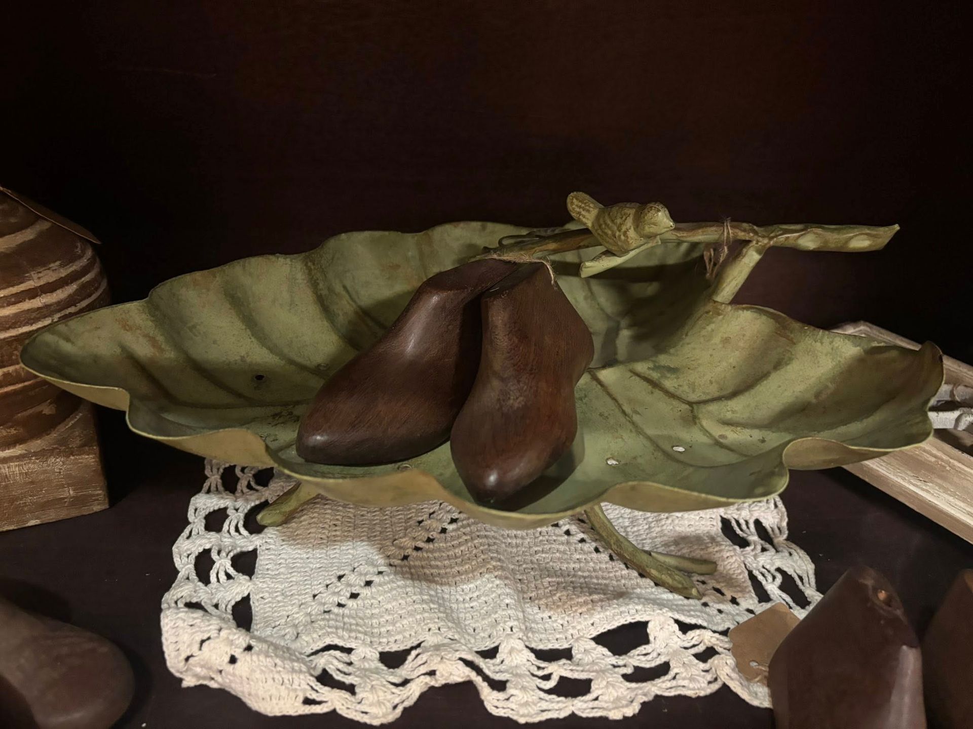 Brown shoes in leaf-shaped dish on lace doily, with a dark backdrop.