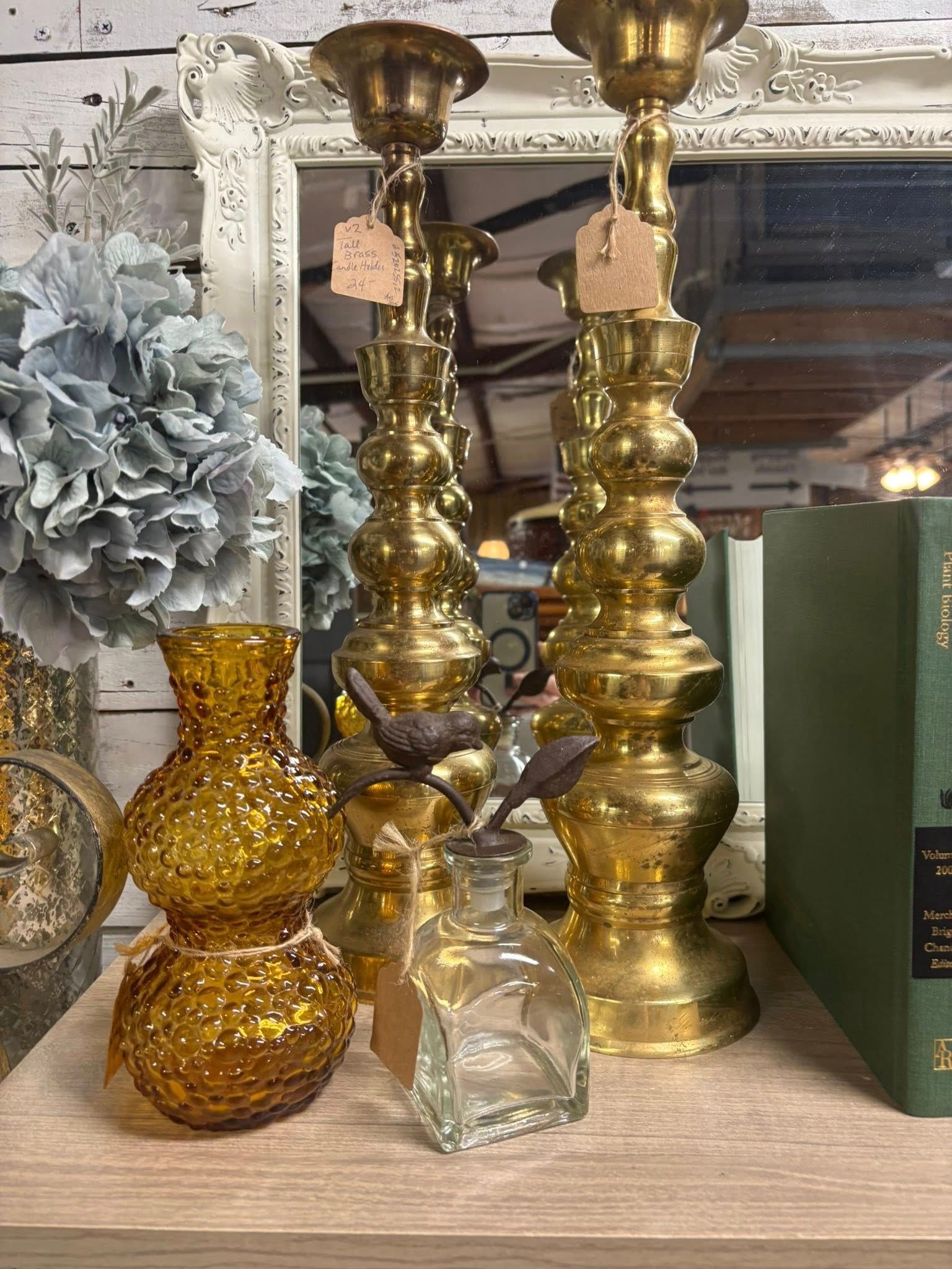 Arrangement of brass candlesticks, amber vases, and books 