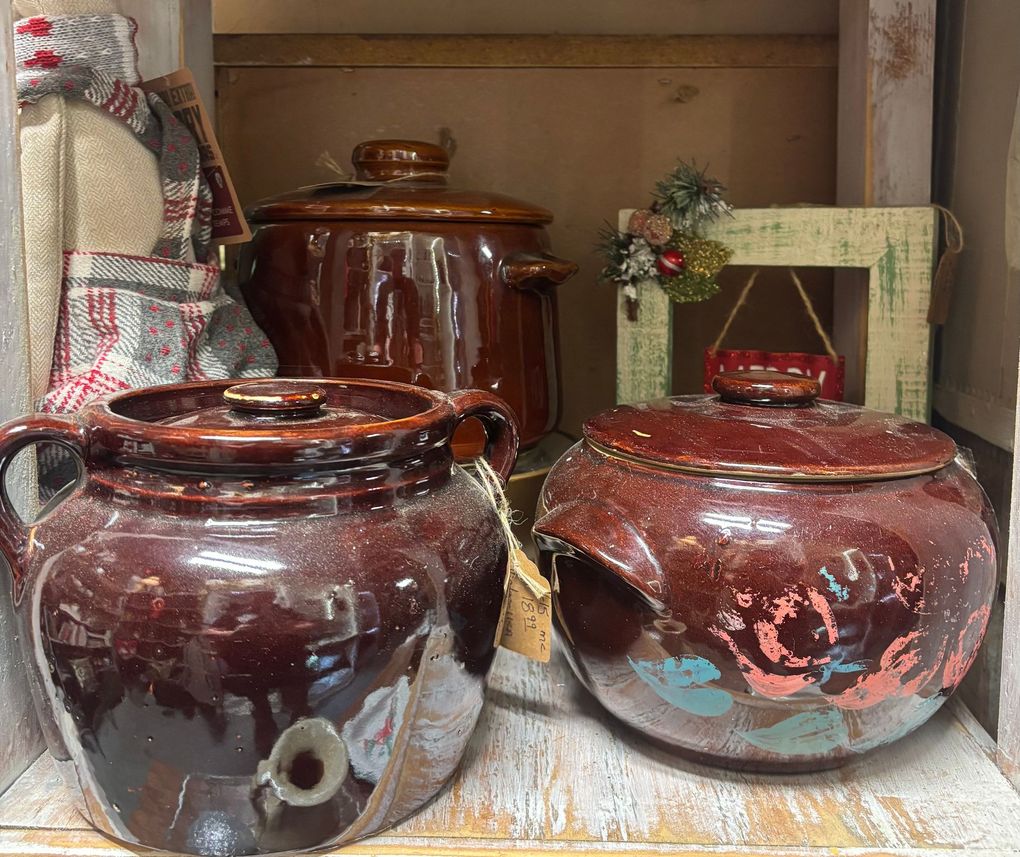 Shelves with rustic pottery, dishes, and a clock, arranged against a gray wall on a wooden table.