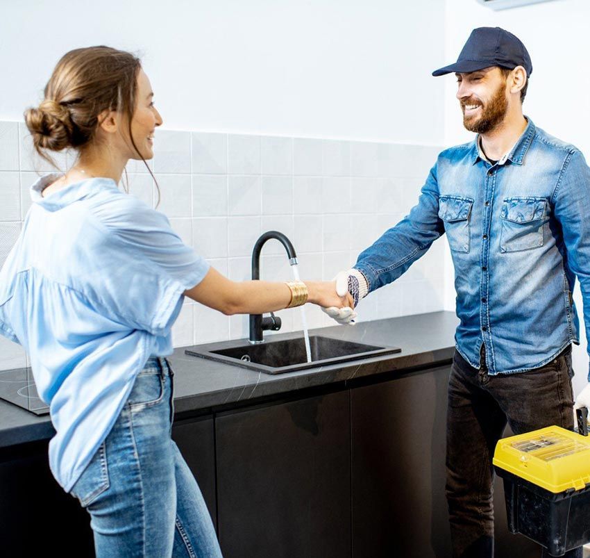A man and a woman are shaking hands in a kitchen.