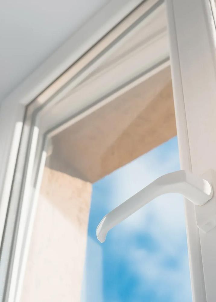 A white window with a handle and a blue sky behind it