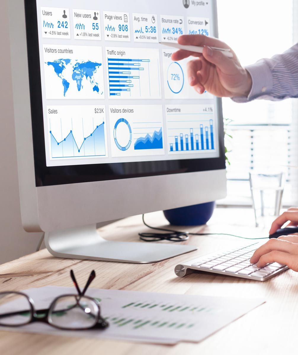 A person is pointing at a computer screen with graphs on it