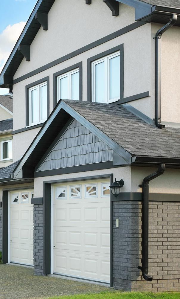 A house with two garage doors and a brick wall.