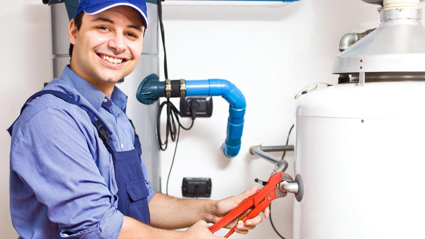 A plumber is fixing a water heater with a wrench.