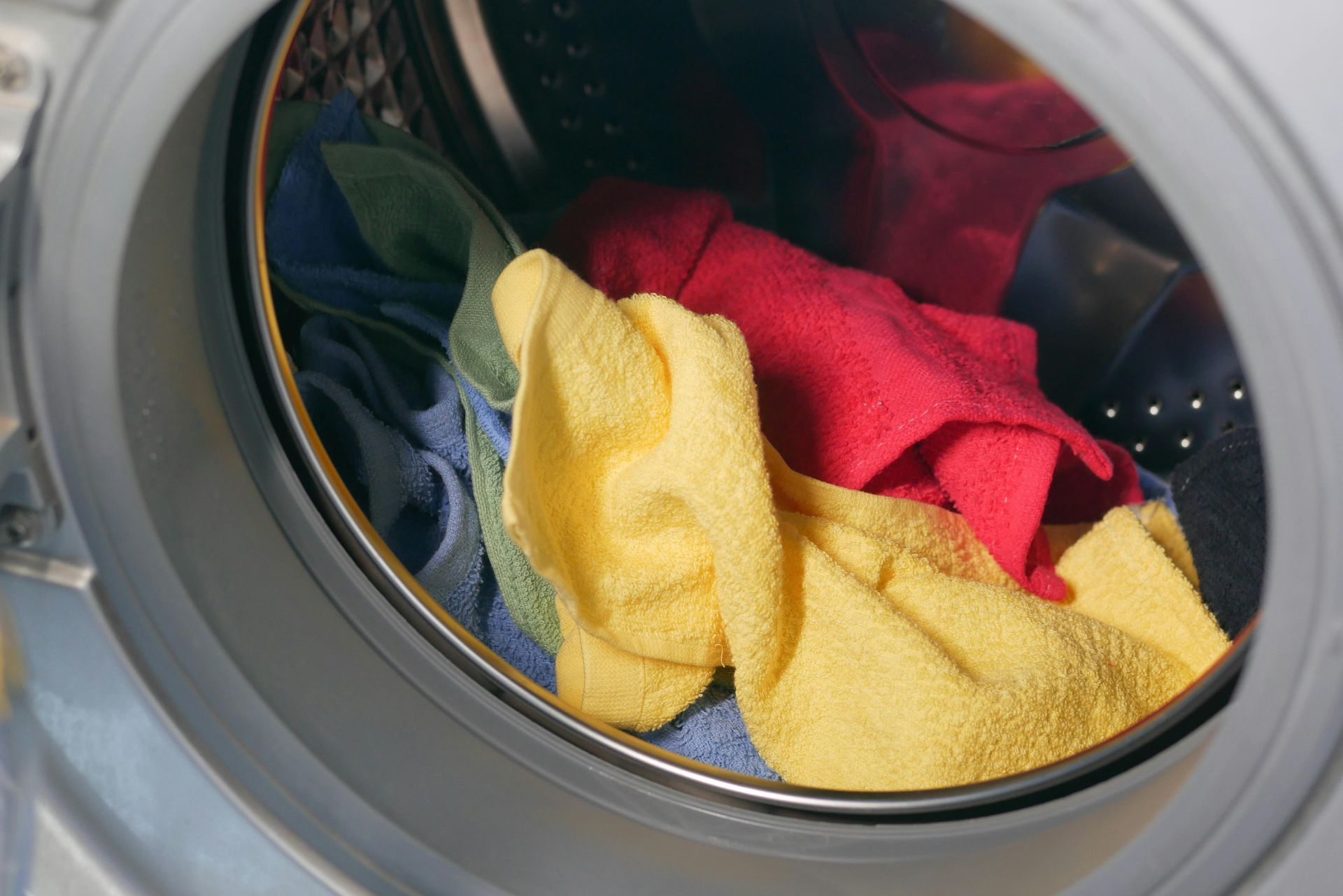 Colorful towels inside a washing machine drum, ready to be washed.