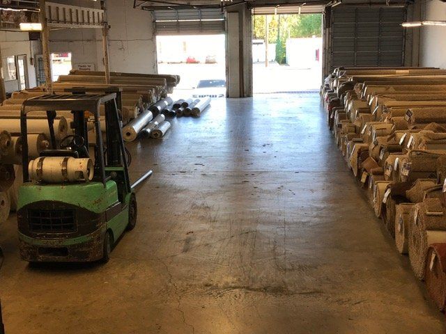 Wood Floors — Rolled Carpets in the Warehouse with Forklift in Austin, TX