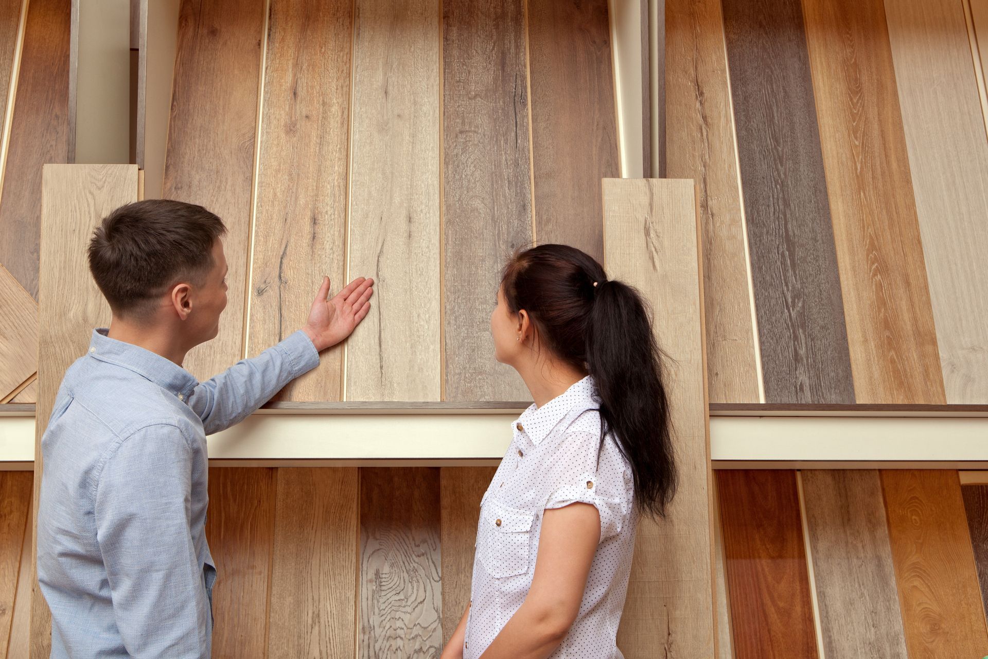 A man is showing a customer the variety of wood floors.