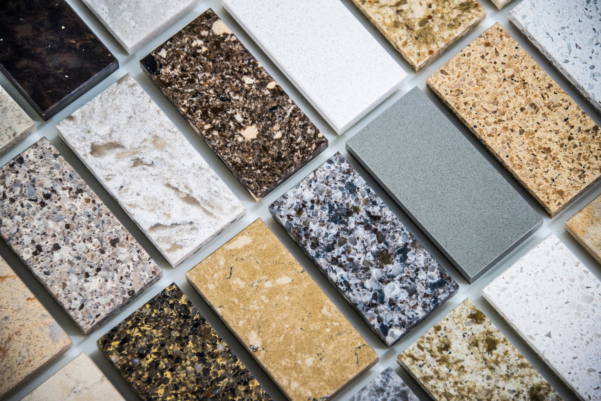 Assorted stone and tile samples displayed in a grid, showing varied colors, textures, and finishes.