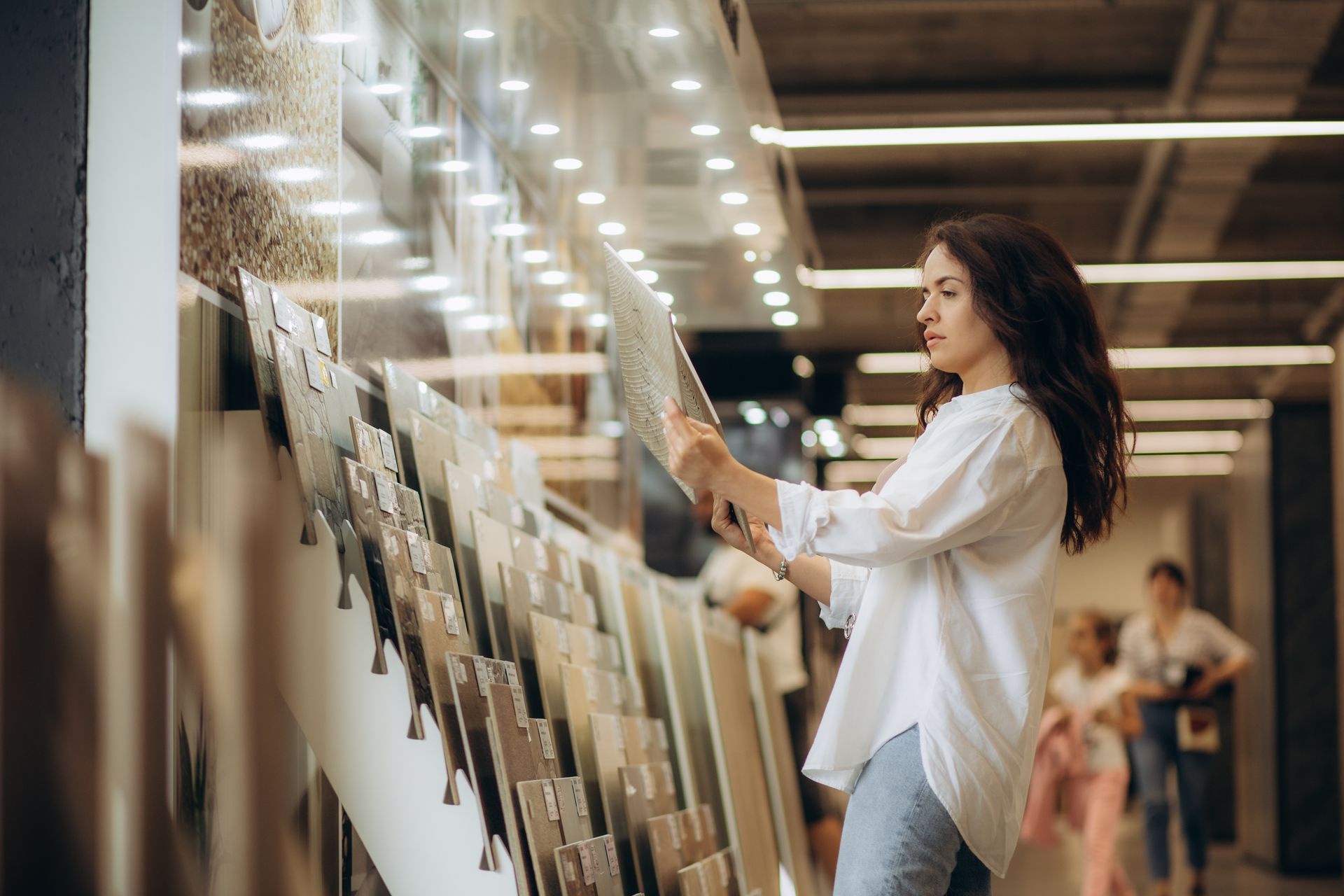A woman is at a flooring store choosing a tile floor.