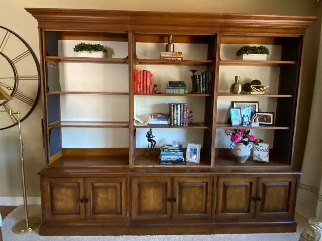 Wooden bookcase with shelves, cabinets, and decorative items in a living room.
