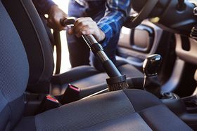 Man Hoovering Seat of Car During Car Cleaning — Ogden, UT — BLH Detailing