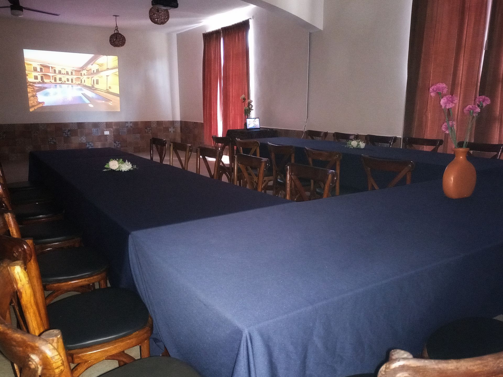 Una sala con mesas y sillas y una pantalla de proyección