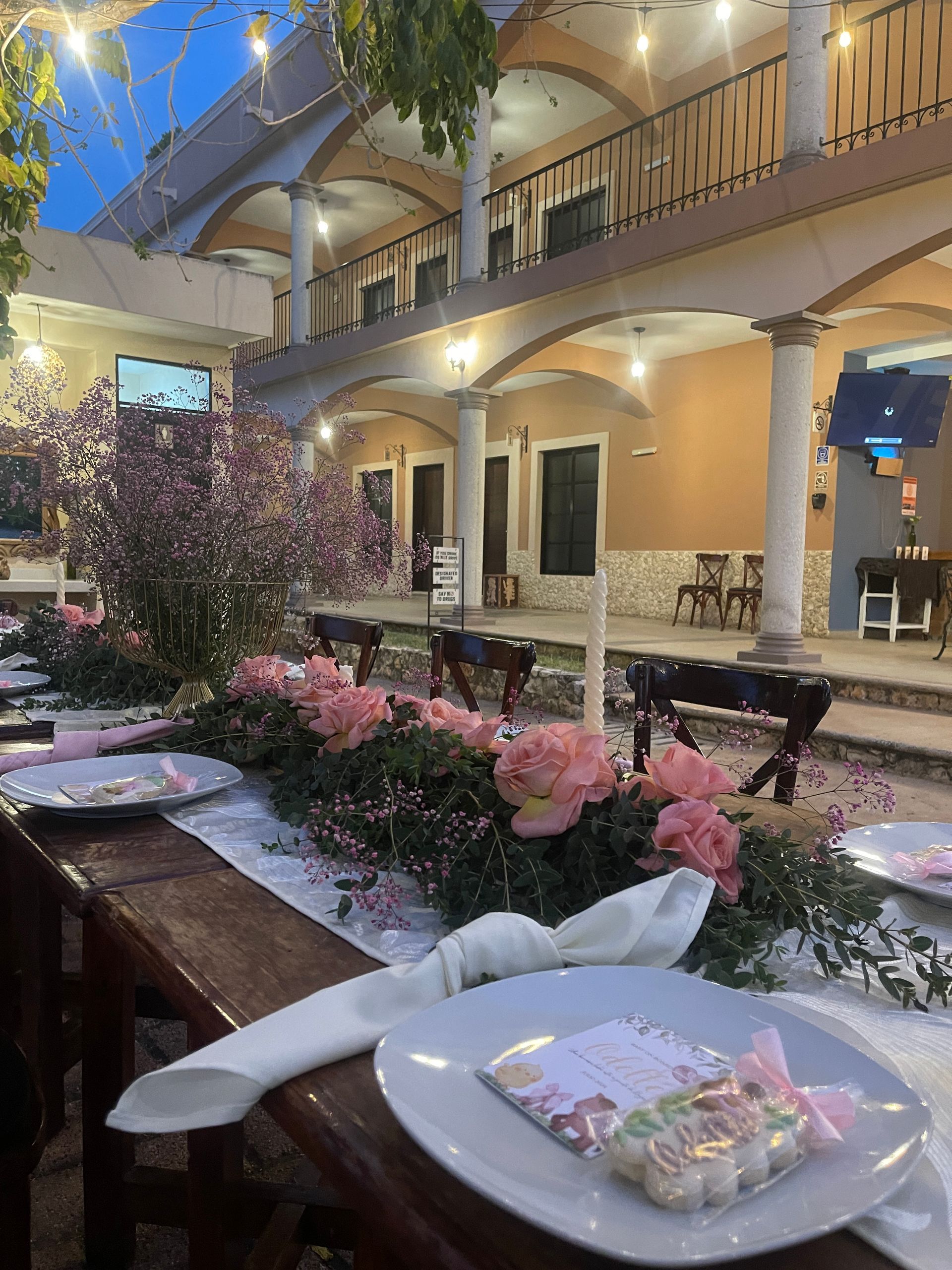 Una mesa larga con platos, servilletas y flores frente a un edificio.