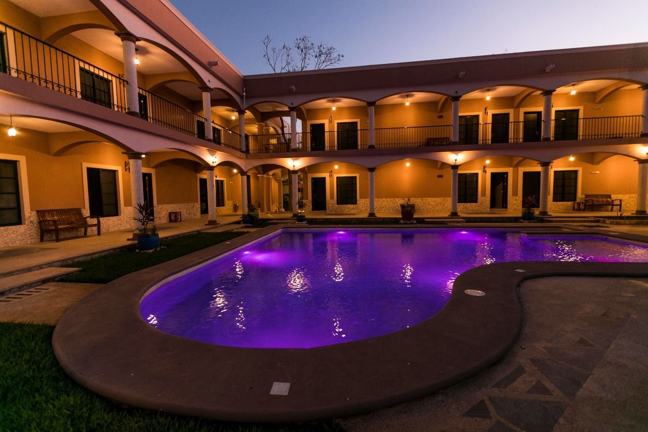 A large swimming pool with purple lights in front of a hotel