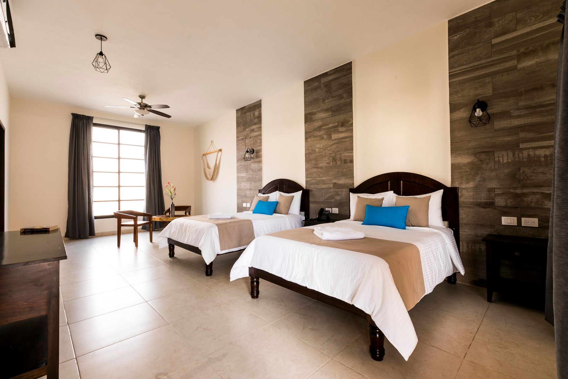 A hotel room with two beds and a ceiling fan.