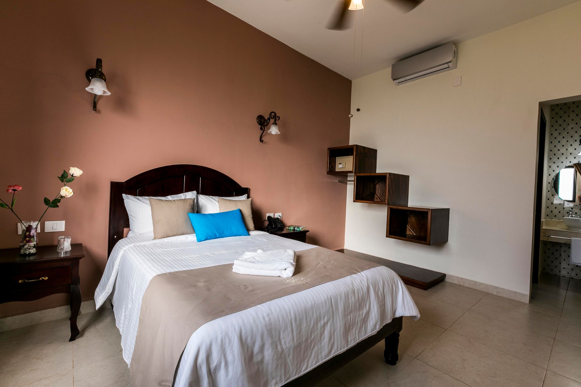 A bedroom with a bed , nightstand , stairs and a ceiling fan.