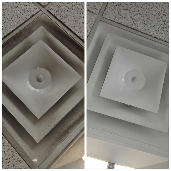 Hands replacing a white air filter in a wall-mounted HVAC unit