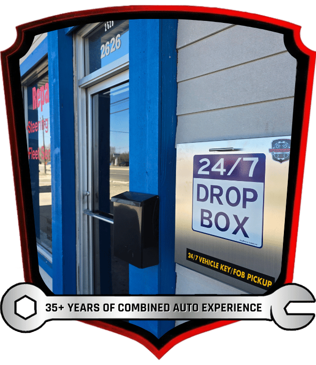 Blue auto shop entrance with 24/7 drop box sign and 35+ years of combined auto experience text inside a wrench