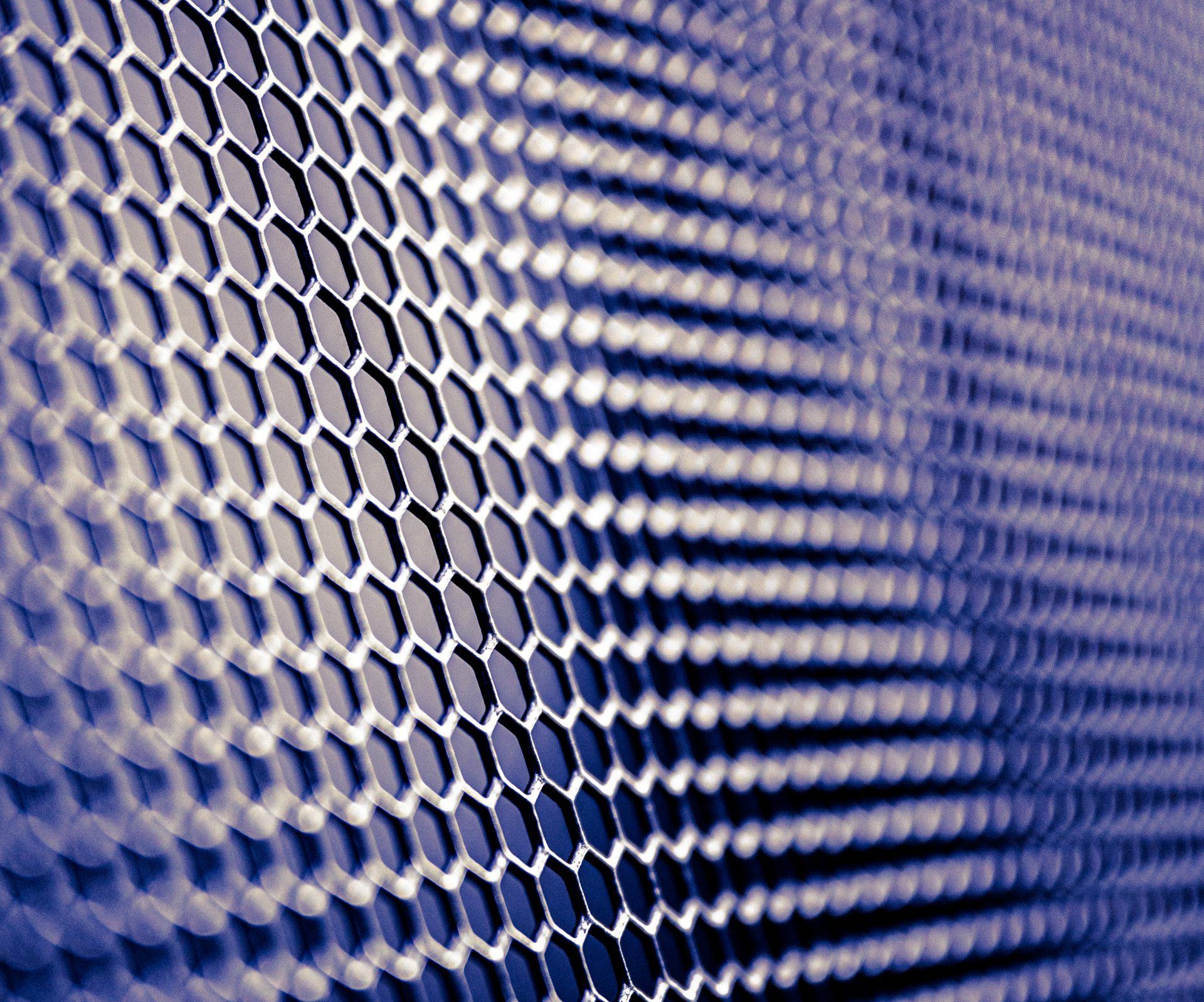 A close up of a metal mesh with a blue background.
