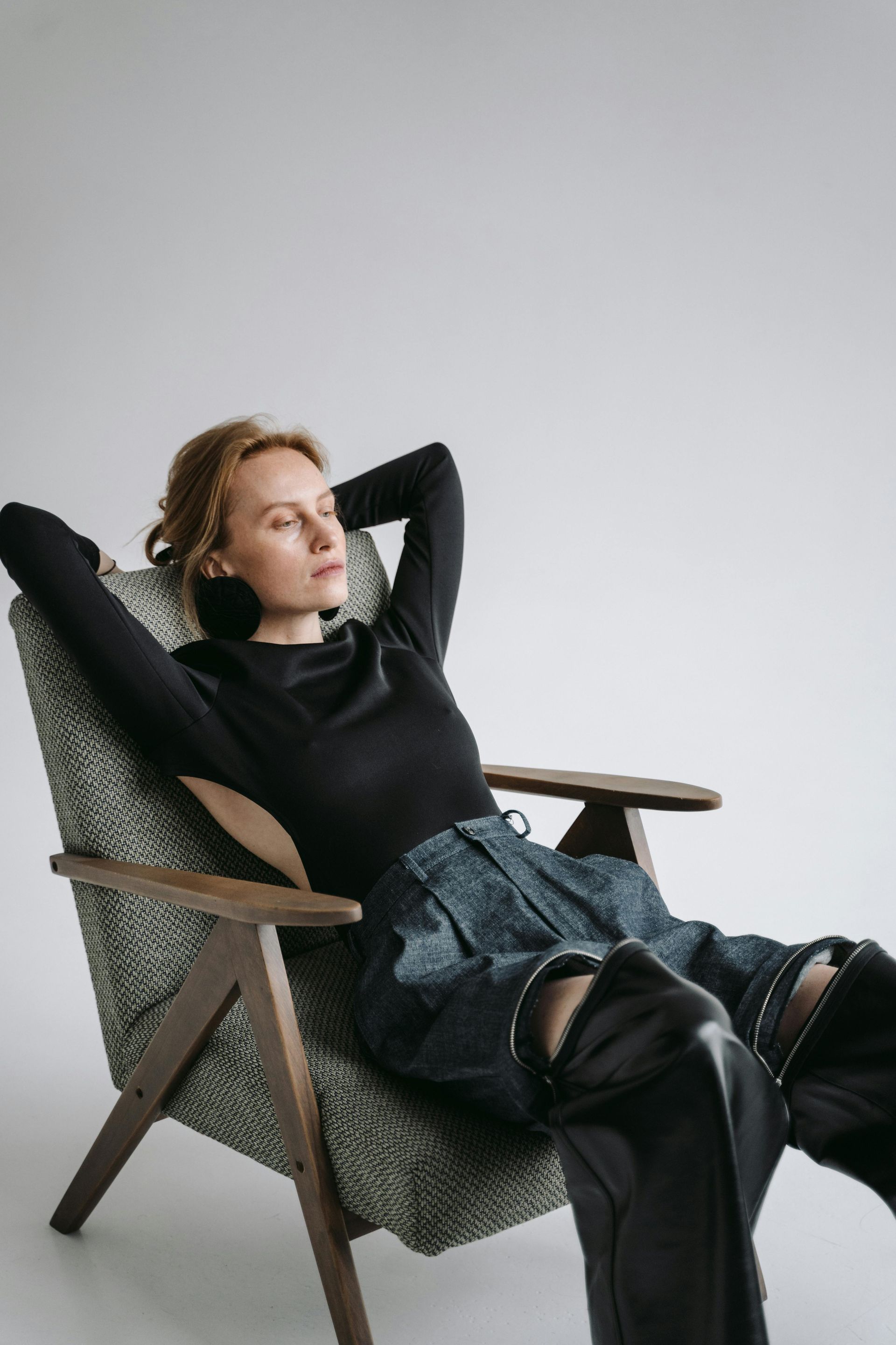A woman taking it easy, sitting in a chair with her hands behind her head.