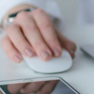 A person is using a computer mouse and a cell phone.