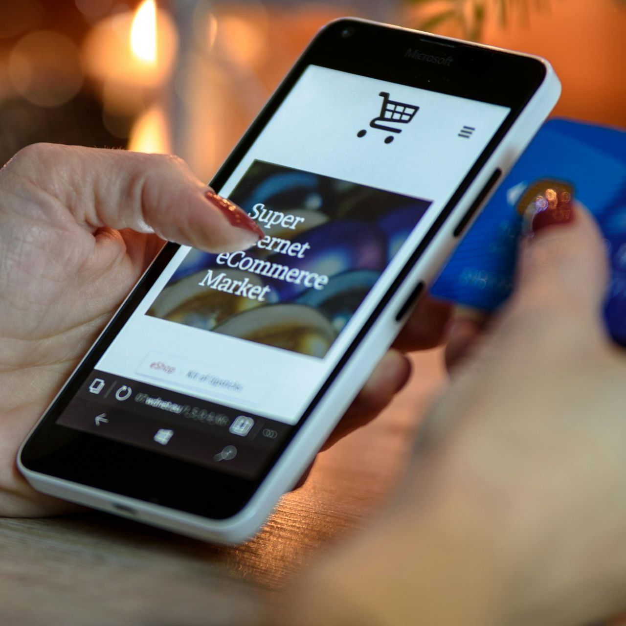 A person holding a credit card and a cell phone that says super internet ecommerce market