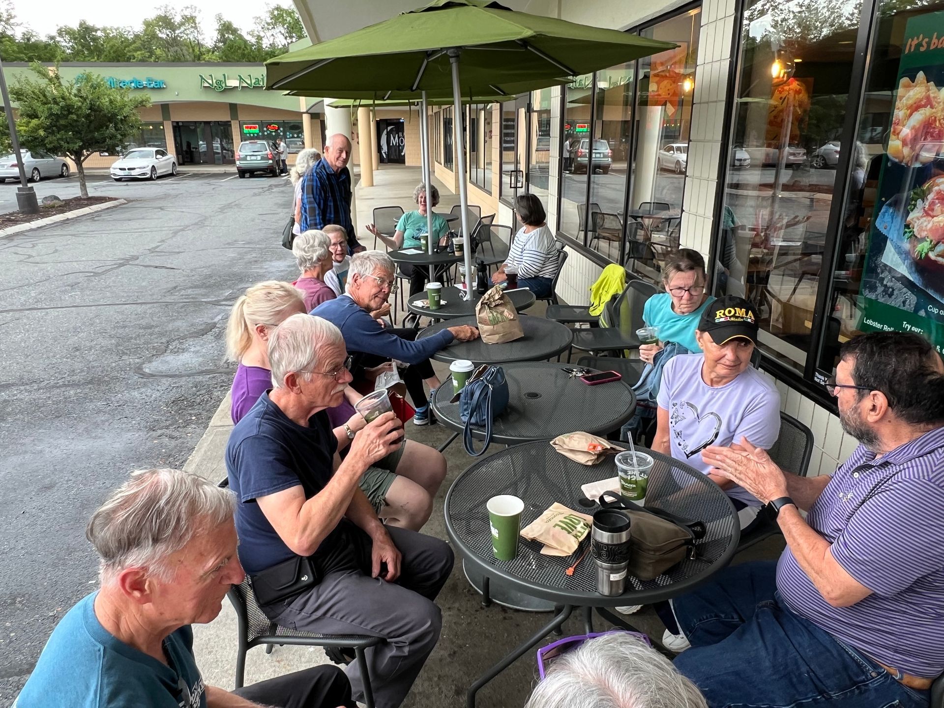 A group of people are sitting at tables outside of a restaurant.